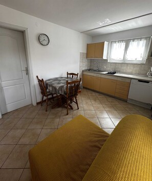 A compact kitchen with a dining table, chairs, a clock, and a window. - MALVINA #4 One-Bedroom Apartment (Rovinj)