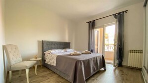 Une chambre à coucher avec un lit, une chaise, une petite table et une fenêtre avec des rideaux.