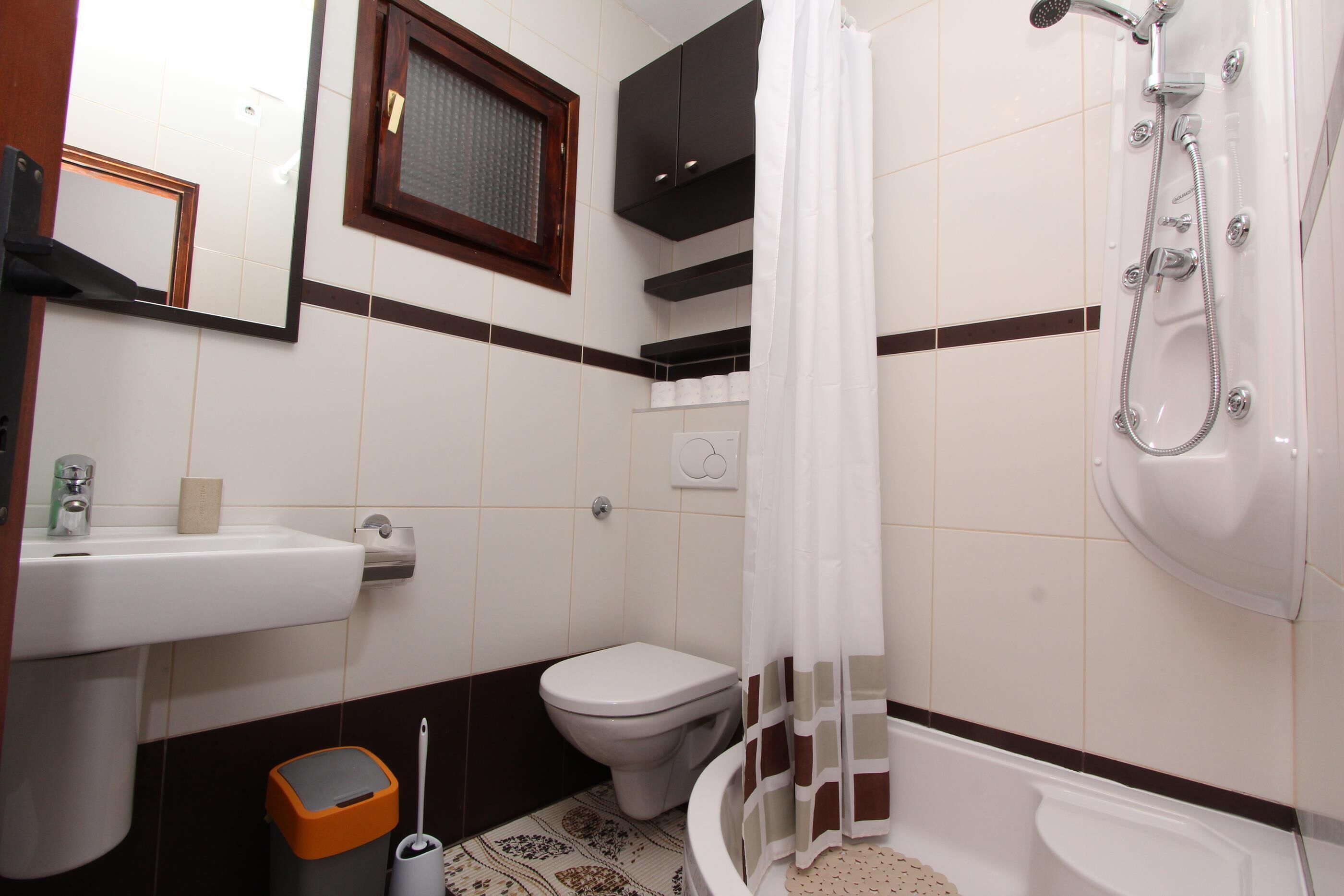 Ein Badezimmer mit Toilette, Waschbecken, Dusche und Mülleimer.
