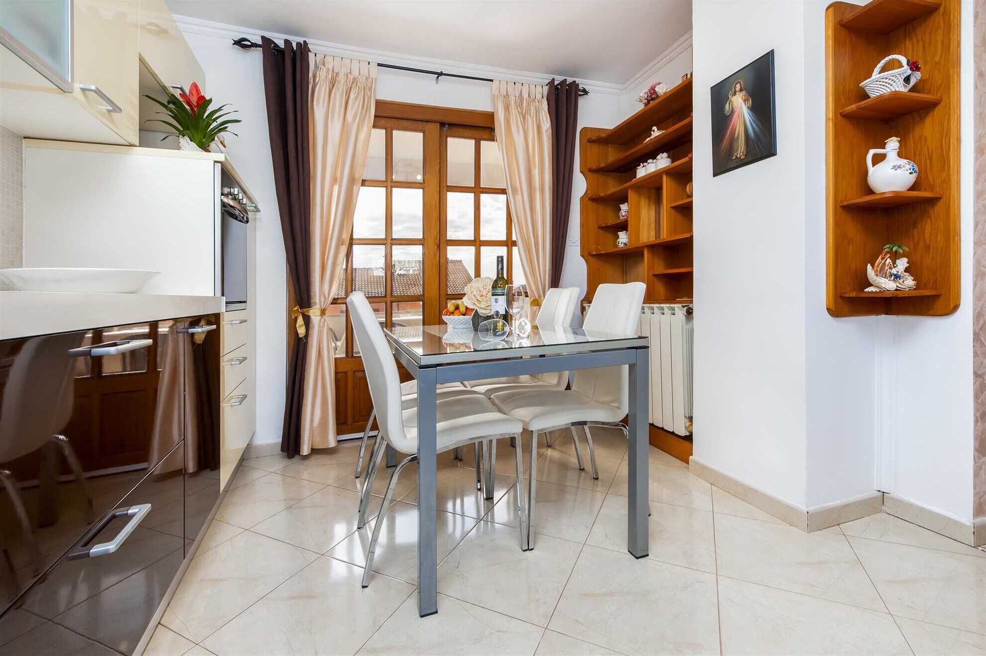 Una cocina moderna con una mesa de comedor, sillas y una ventana con cortinas.