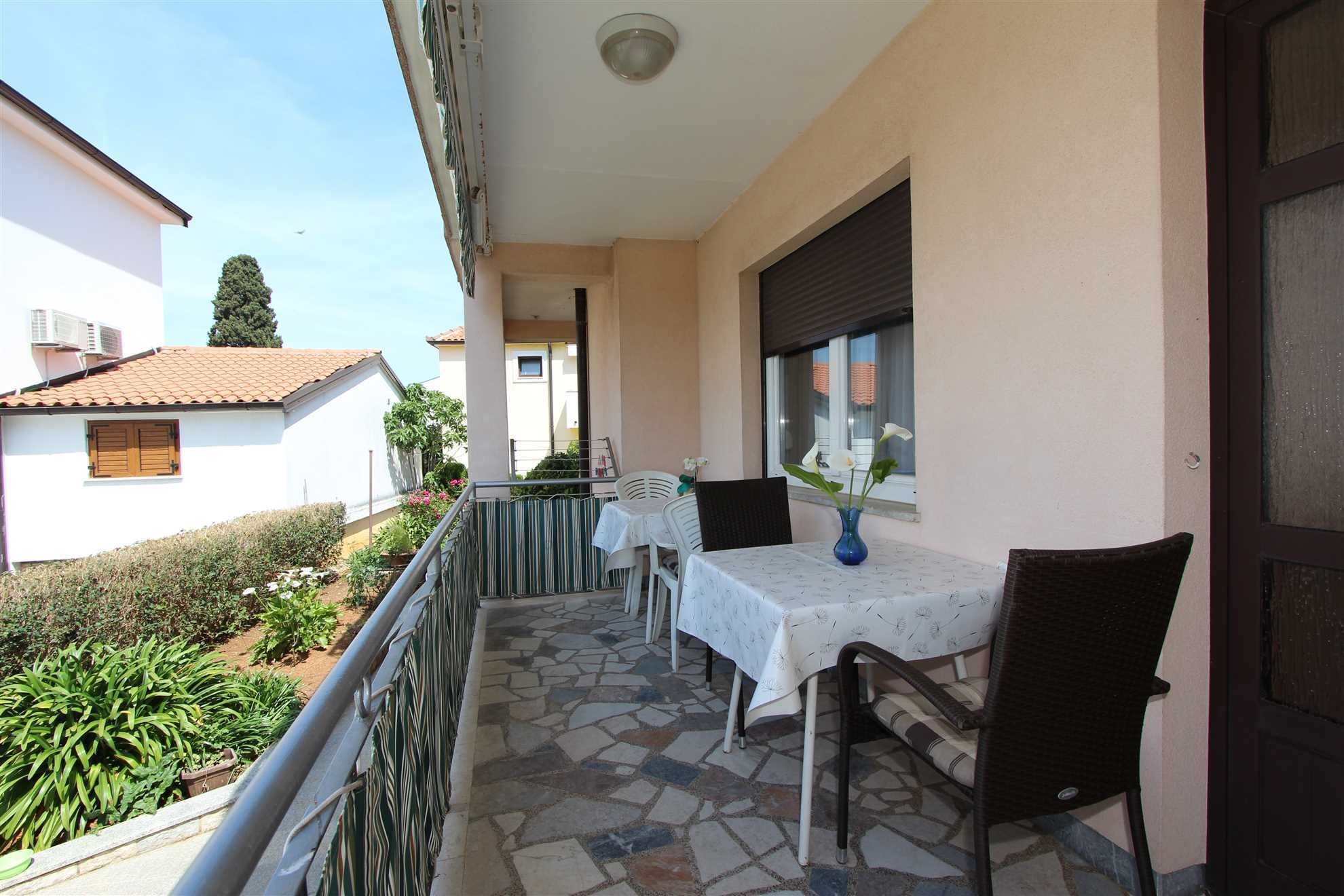 A balcony with a table and chairs, a window with a view, and a door.