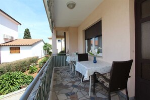 Un balcon avec une table et des chaises, une fenêtre donnant sur un paysage agréable et une porte.