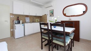 A compact kitchen with white cabinets, a microwave, a refrigerator, and a dining area with a table and chairs.