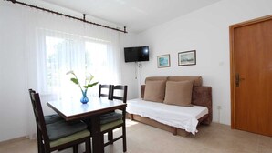 A room with a dining table, chairs, a sofa, a television, and a door.