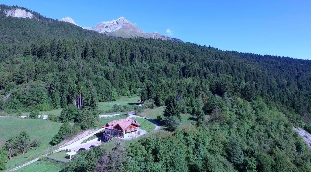 Eine Berghütte mit rotem Dach, umgeben von dichtem Wald und freiem Blick auf ein Gebirge.