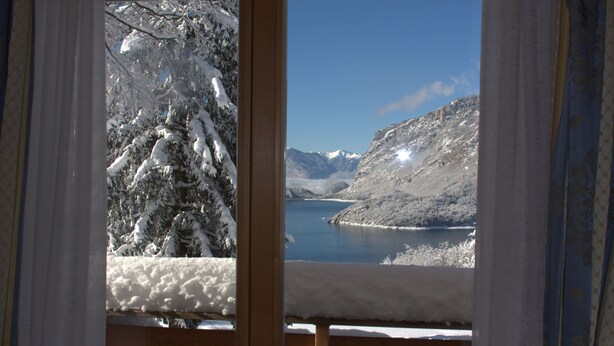 Une cabane en bois offrant une vue sur une montagne enneigée et un lac.