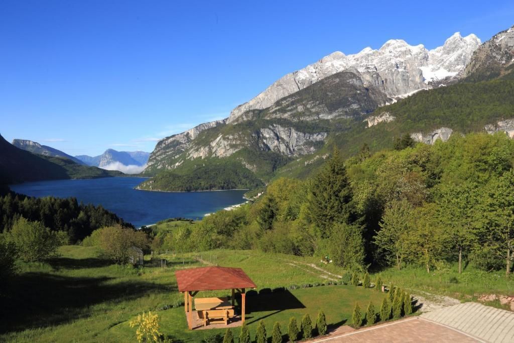 A mountainous landscape with a lake, a wooden gazebo, and a clear sky.