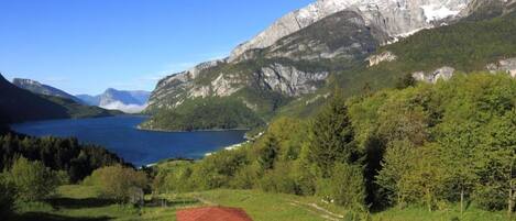 A mountainous landscape with a lake, a wooden gazebo, and a clear sky.