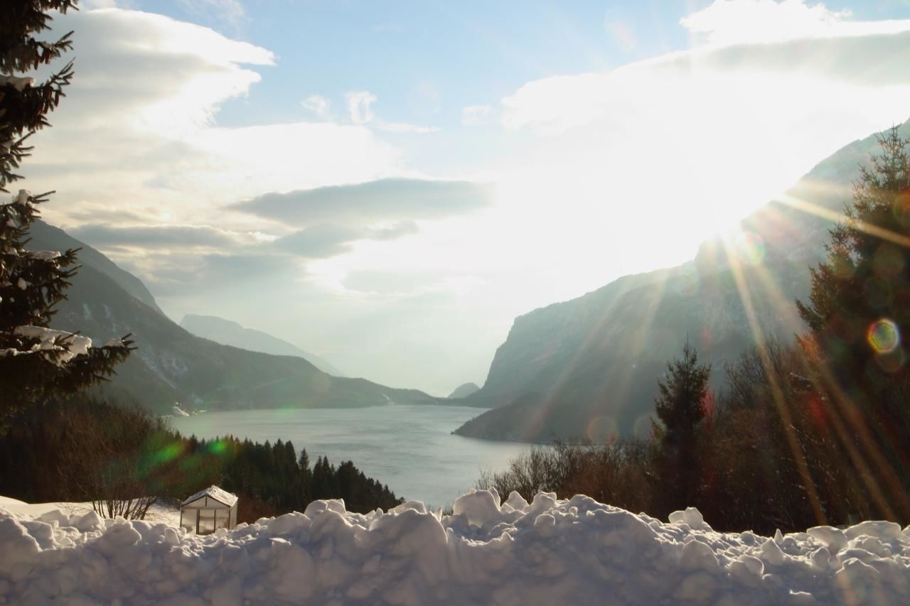 Paisagem coberta de neve com um lago, montanhas e uma pequena cabana.