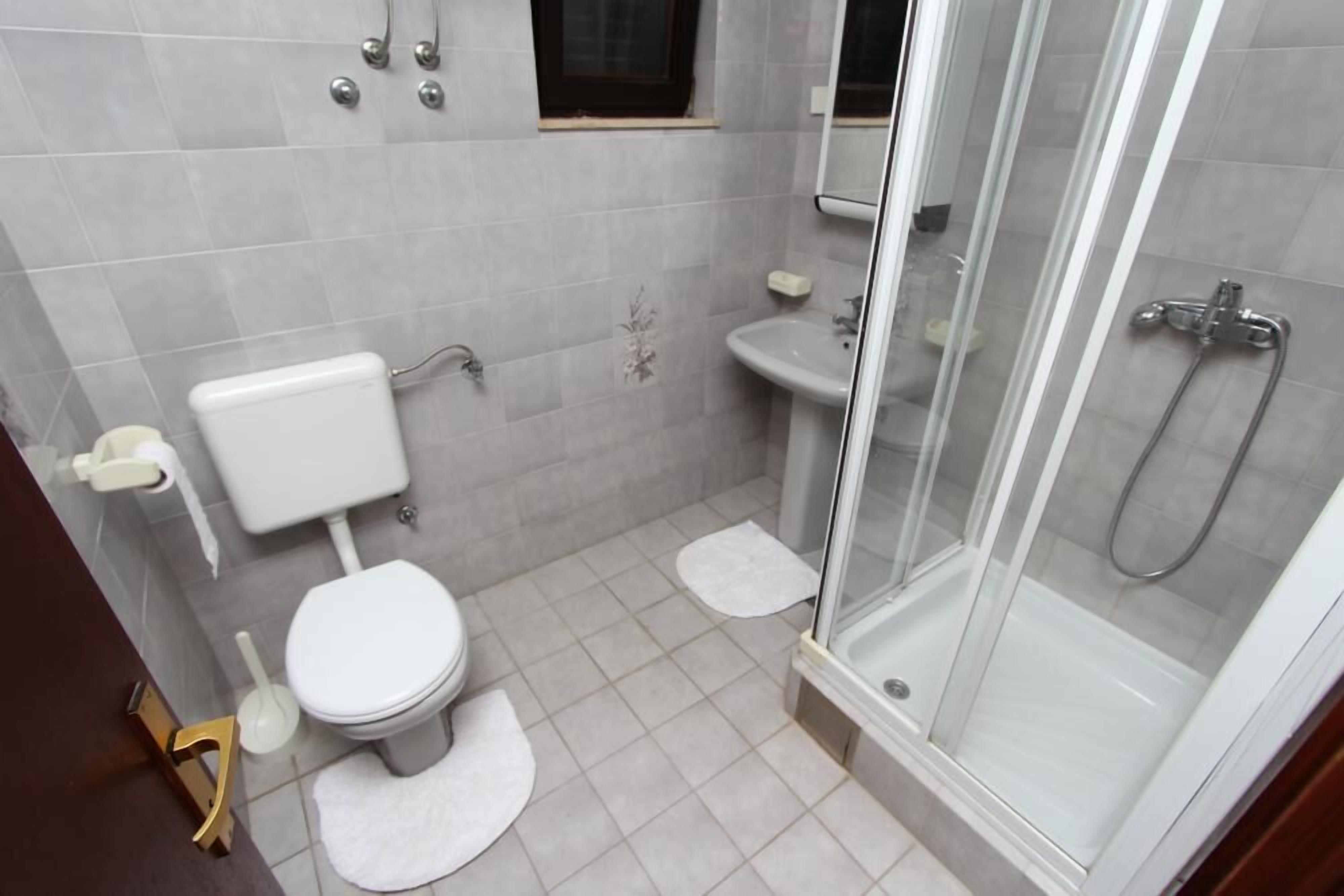 A small bathroom with a toilet, sink, and glass shower enclosure.
