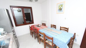 A dining area with a table, chairs, a window, and a radiator. - NATALI Three-Bedroom Apartment (Rovinj)