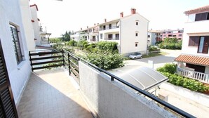 A residential building with a balcony, a car parked in the driveway, and a neighboring building with a red-tiled roof. - NATALI Three-Bedroom Apartment (Rovinj)