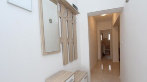 A hallway with a wooden console table, a mirror, and a door leading to a bathroom. - PALAZIOL Two-Bedroom Apartment 1 (Rovinj)