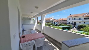 A balcony with a table and chairs, a small kitchen area, and a view of residential buildings. - PALAZIOL Two-Bedroom Apartment 1 (Rovinj)