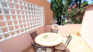 A round table with four chairs, a white lattice window, and potted plants. - LUCU One-Bedroom Apartment (veći) (Rovinj)