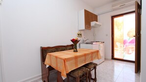 Un comedor con una mesa cubierta por un mantel a cuadros, sillas de madera y un florero con flores.