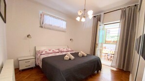 Un dormitorio con cama, una mesita de noche, una ventana con cortinas y vistas al exterior.