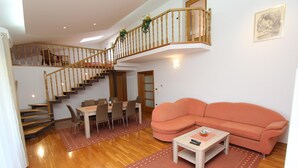 A spacious living area with a wooden staircase, a dining table, and a sofa. - VILLA NERA Three-Bedroom Apartment (Pula)
