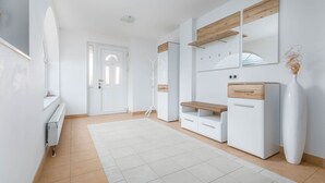 A modern, well-lit hallway with a white door, a white radiator, and a white tiled floor. - VILLA NERA Three-Bedroom Apartment (Pula)