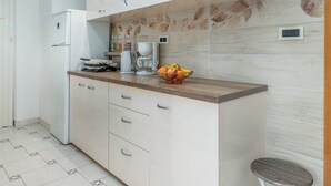 A modern kitchen with white cabinets, a wooden countertop, and a tiled backsplash. - VILLA NERA Three-Bedroom Apartment (Pula)