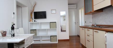 A modern kitchen with white cabinets, a built-in oven, and a large window.