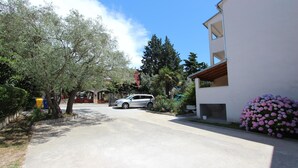 Una calle residencial con un edificio blanco, coches aparcados y árboles.
