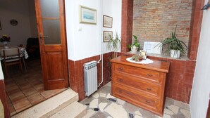 A room with a wooden door, a radiator, a dresser, and a brick wall. - RIKI Two-Bedroom Apartment (Rovinj)