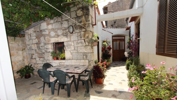 A stone building with a tiled patio, outdoor seating, and potted plants. - RIKI Two-Bedroom Apartment (Rovinj)