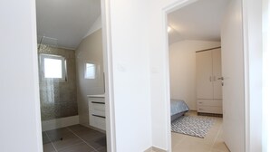 A hotel room with a shower, a bed, a wardrobe, and a small window. - SORRISO One-Bedroom Apartment (Rovinj)