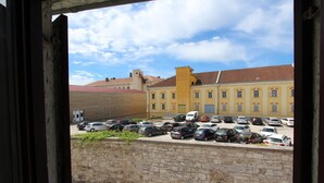 A courtyard with a parking lot, stone wall, and yellow buildings with red roofs. - SORRISO One-Bedroom Apartment (Rovinj)