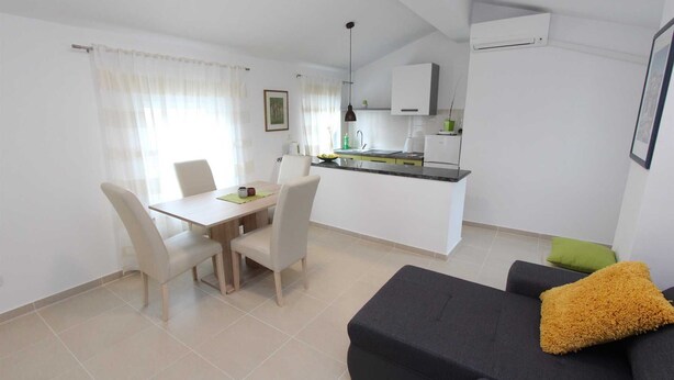 A modern apartment with a dining area, kitchenette, and a living room with a sofa and a small table. - SORRISO One-Bedroom Apartment (Rovinj)