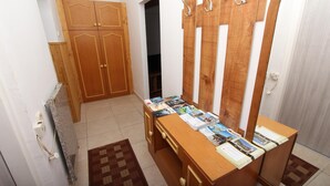 A room with a wooden wardrobe, a desk with magazines, and a patterned rug. - PUPA Studio Apartment (Rovinj)