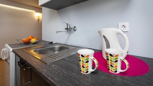 A kitchen with a sink, a kettle, and two mugs on a pink mat. - SILVANA One-Bedroom Apartment with Terrace 2 (donji) (Rovinj)