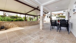 An outdoor patio with a covered seating area, stone flooring, and a view of a residential street. - SILVANA One-Bedroom Apartment with Terrace 2 (donji) (Rovinj)