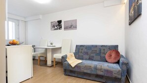 A compact living space with a kitchenette, a dining area, and a sofa with a patterned cover. - SILVANA One-Bedroom Apartment with Terrace 2 (donji) (Rovinj)