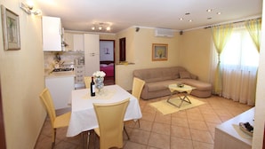 Espaço compacto com cozinha compacta, área de refeições e sofá.
