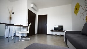 A modern living room with a sofa, a TV, a dining area with chairs, and a kitchen area. - BERTETIC One-Bedroom Apartment 3 (Pilkovici)