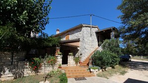 A stone house with a wooden staircase leading to the entrance, surrounded by greenery and a clear blue sky. - BERTETIC One-Bedroom Apartment 3 (Pilkovici)