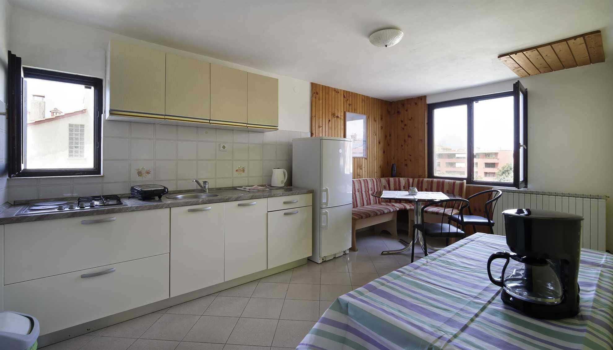 Cocina compacta con comedor, refrigerador, estufa y cafetera.