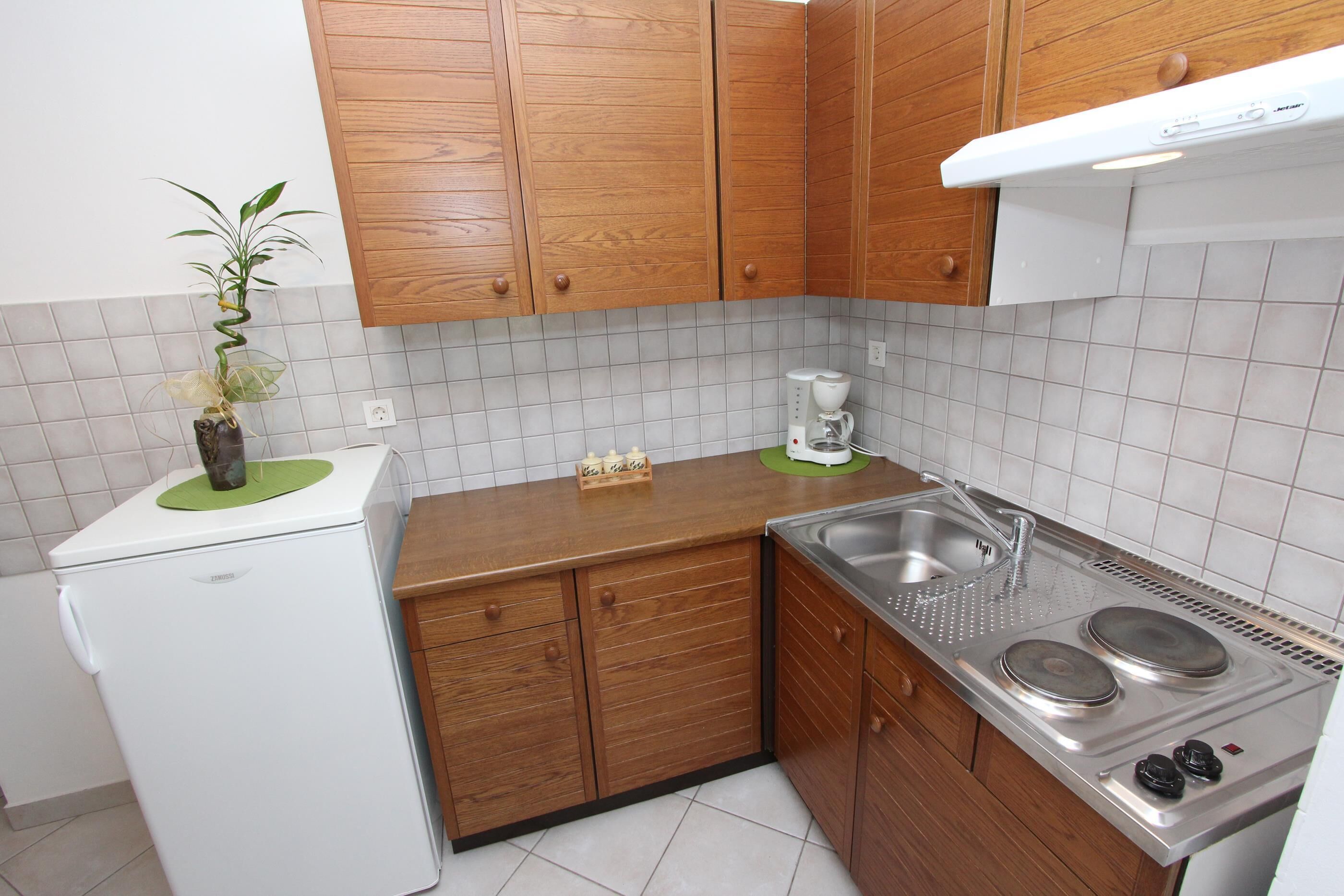 Une cuisine compacte avec des meubles en bois, un réfrigérateur blanc, une cuisinière encastrée et un évier.