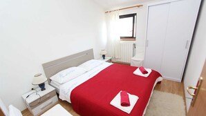 Et hotelværelse med en seng, et natbord, en lampe og et klædeskab.
