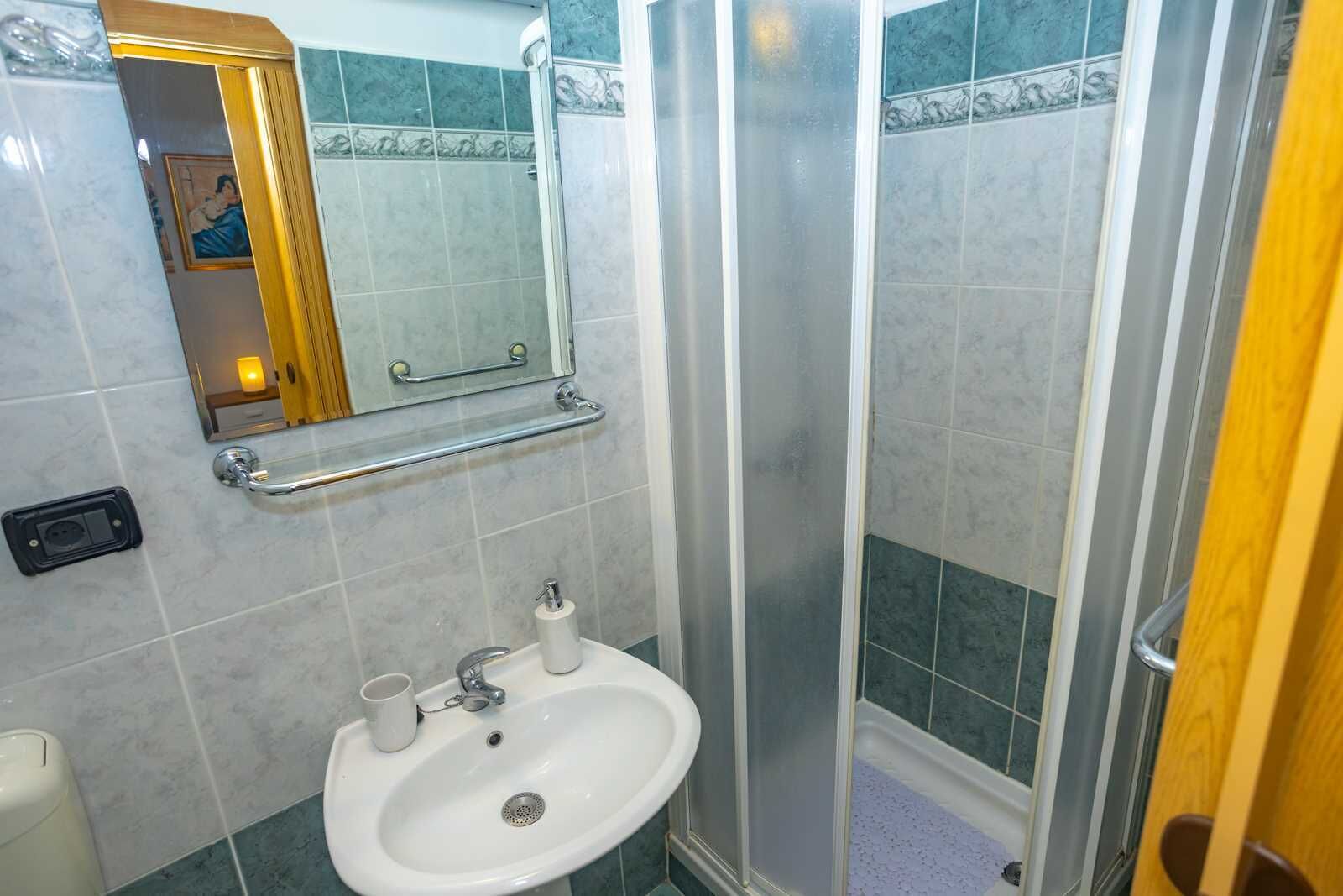 Une salle de bain avec un lavabo, un miroir et une douche.