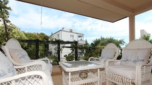 A covered patio area with wicker furniture, including two chairs and a small table, under a pergola.