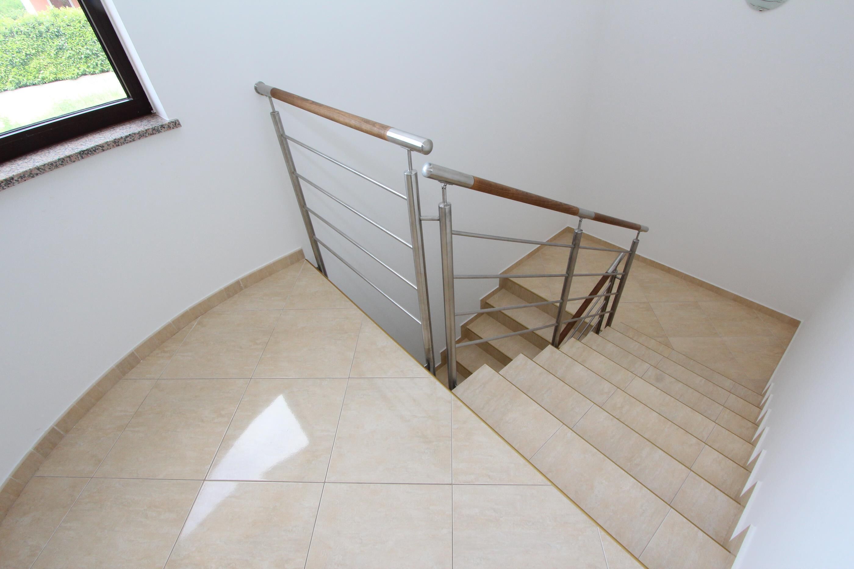 A staircase with a metal handrail and wooden steps, leading to an upper floor.