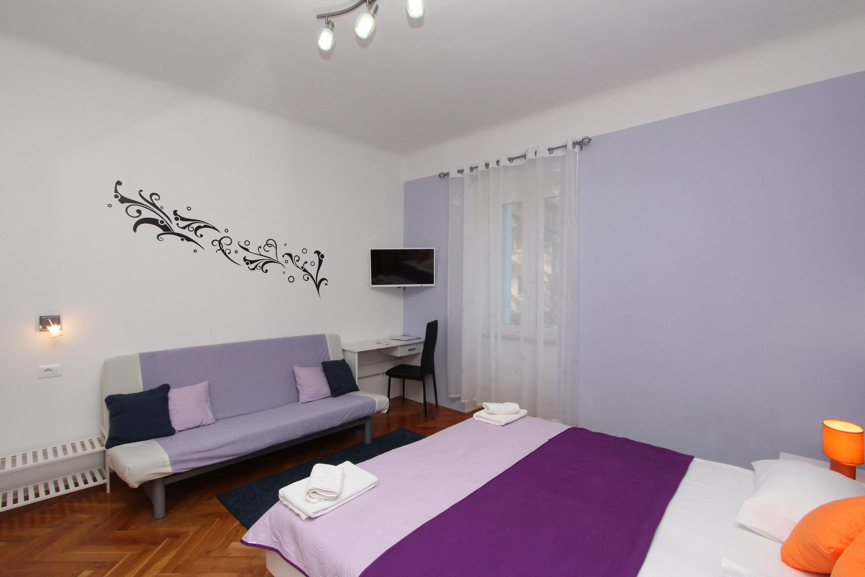 Une chambre à coucher moderne avec un lit, un canapé, un bureau et un téléviseur.