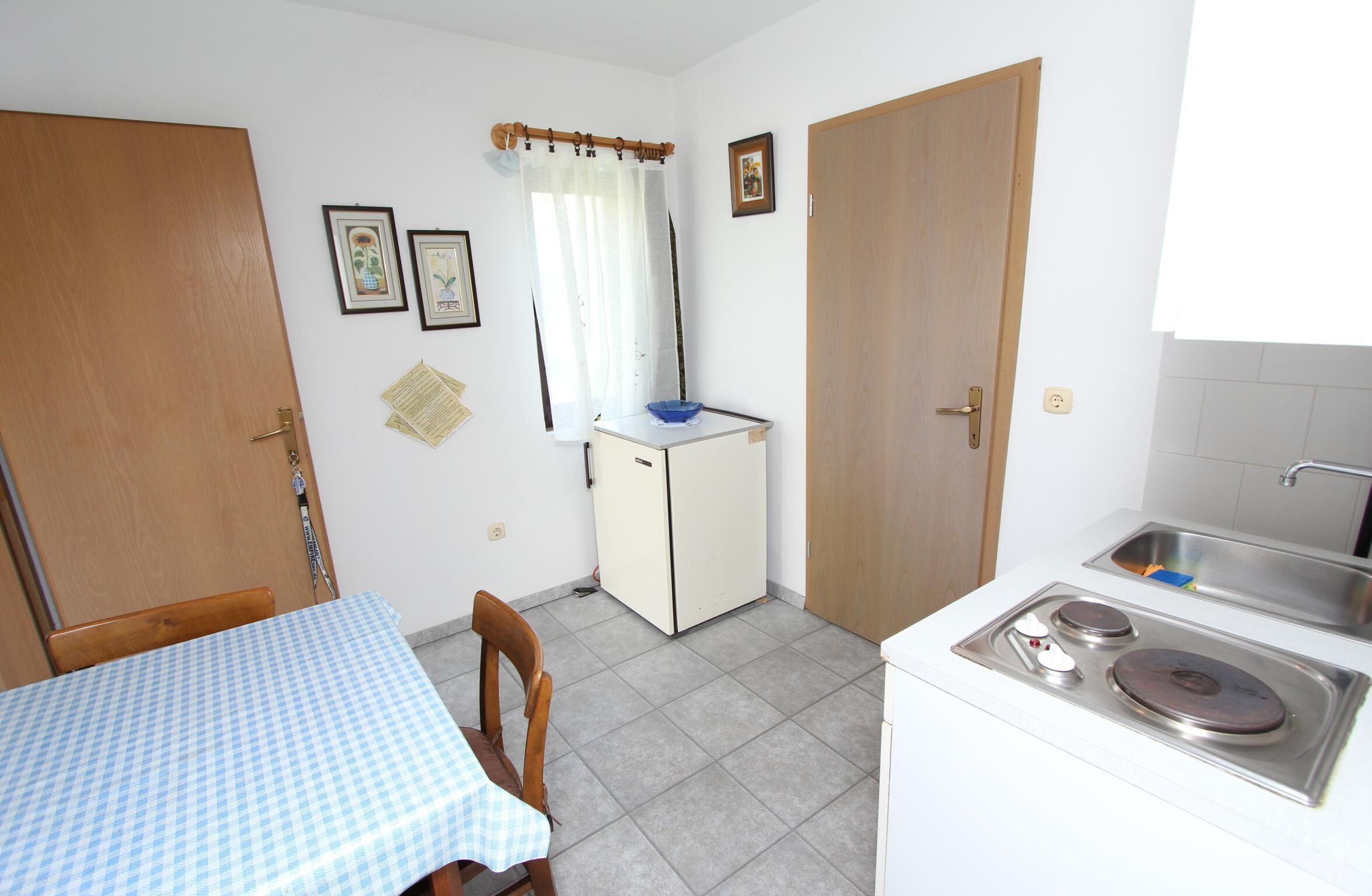 A compact kitchen with a dining table, a refrigerator, a sink, and a stove.