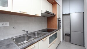 Eine moderne Küche mit Edelstahlgeräten, weißen Schränken und einer grauen Arbeitsplatte.