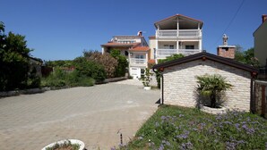 Un quartier résidentiel avec une allée pavée menant à une maison à deux étages dotée d’un balcon.