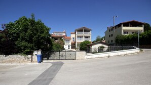 Un quartier résidentiel avec une route asphaltée, un mur en pierre et une poubelle bleue.