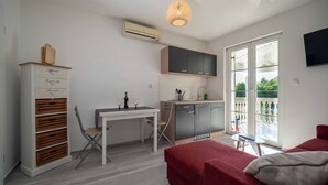 Un espace de vie compact comprenant un coin cuisine, un coin repas et un lit.